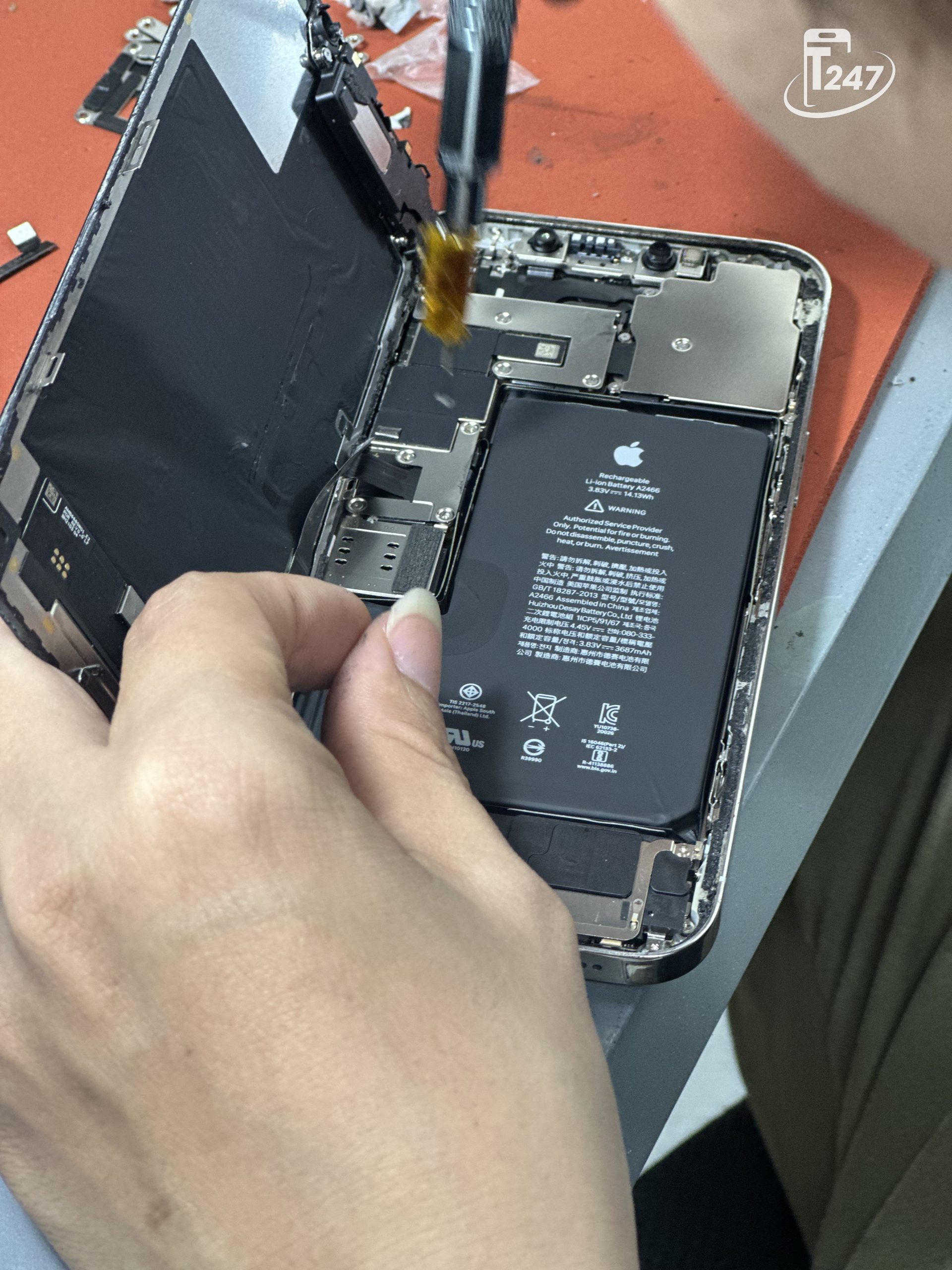 Kỹ thuật viên Táo 247 đang đo đạc bo mạch để sửa phần cứng iPhone mất sóng trên bàn máy móc hiện đại 